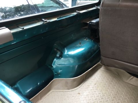 1996 Ford Bronco - The interior cargo area of a 1996 Ford Bronco shows a green painted wheel well and a tan floor mat.