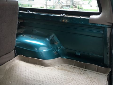 1996 Ford Bronco - Interior view of the cargo area in a 1996 Ford Bronco, showing the teal paint and rubber floor mat.