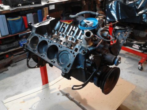 1978 Ford Bronco - Engine block assembly with visible cylinders and pulley system, mounted on a red engine stand.