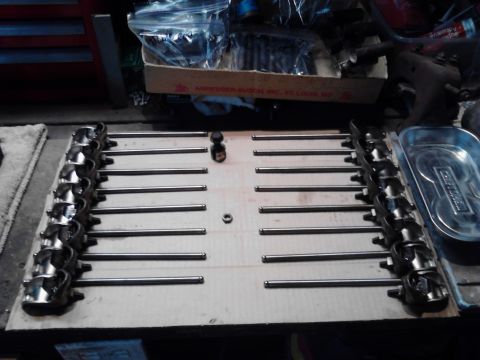 1978 Ford Bronco - Engine valve train components, including rocker arms and pushrods, are organized on a piece of cardboard.