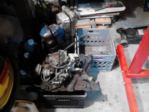1978 Ford Bronco - An engine part sits on a crate, with various items and a red engine stand in the background.