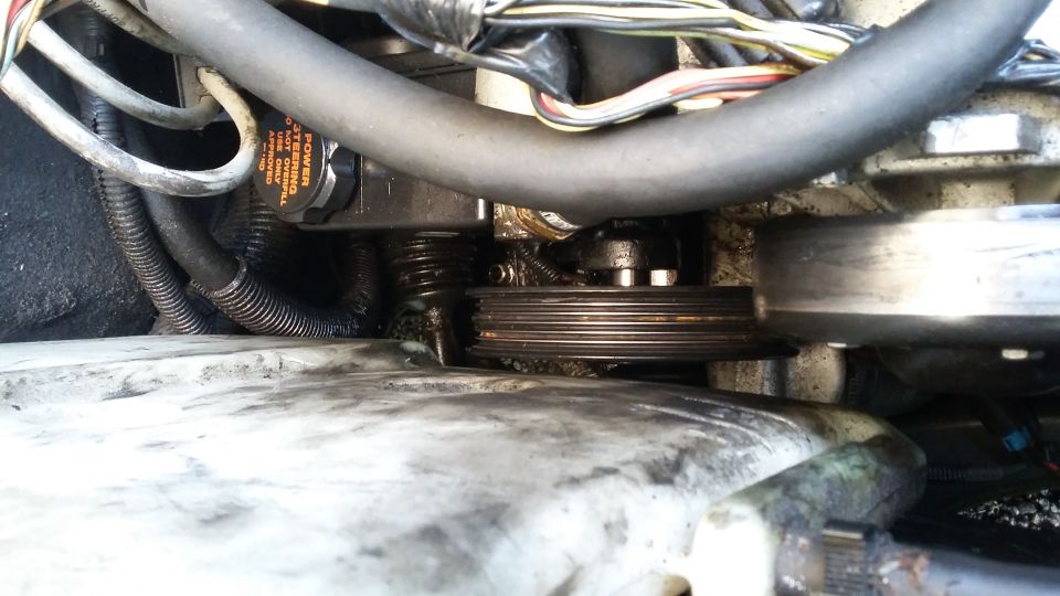 Close-up of a ribbed pulley and power steering pump with orange cap