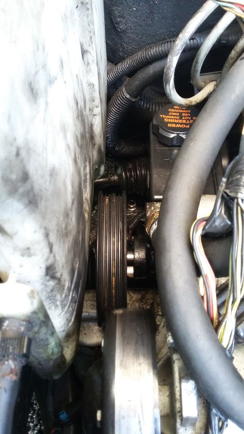 Close-up of engine pulley and power steering fluid reservoir with cap reading 'POWER STEERING FLUID ONLY'