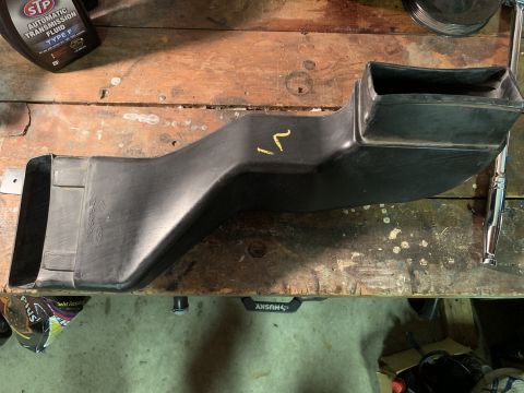 1996 Ford Bronco - A black plastic air duct is shown on a workbench, with a bottle of STP automatic transmission fluid nearby.