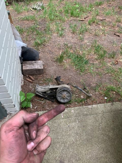 1996 Ford Bronco - A dirty automotive part is shown on the ground next to a building and some grass.
