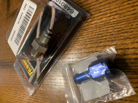 1996 Ford Bronco - Close-up of two new automotive hose fittings, one metal and one blue, still in their original packaging.