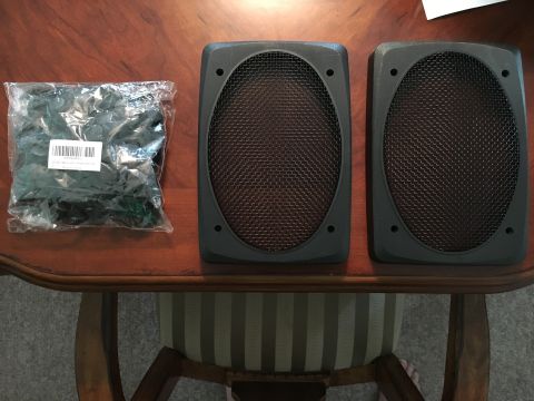 1996 Ford Bronco - Pair of speaker grilles and a bag of fasteners are laid out on a wooden table.
