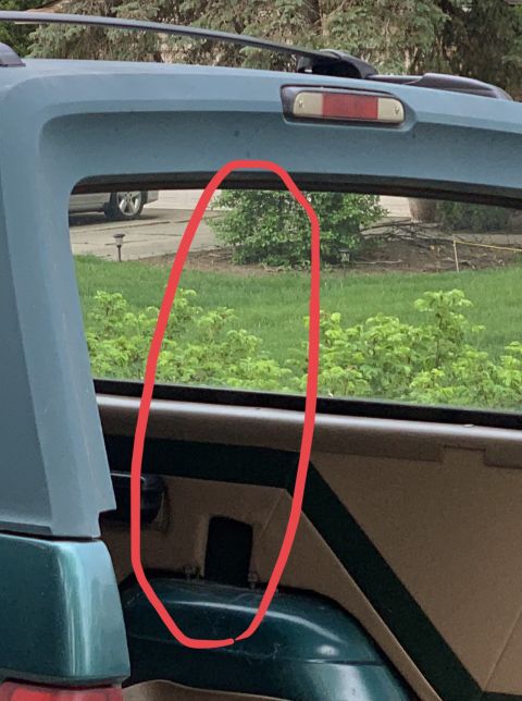 1996 Ford Bronco - The rear window of an SUV is shown, with a red circle highlighting a portion of the view outside.