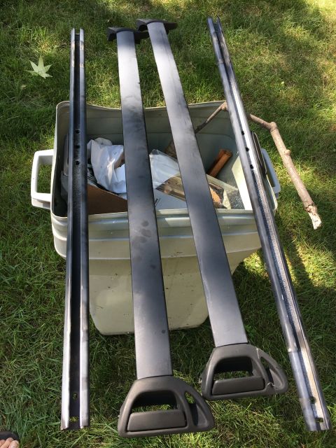 1996 Ford Bronco - Roof rack components are shown disassembled, placed on grass next to a plastic storage container.