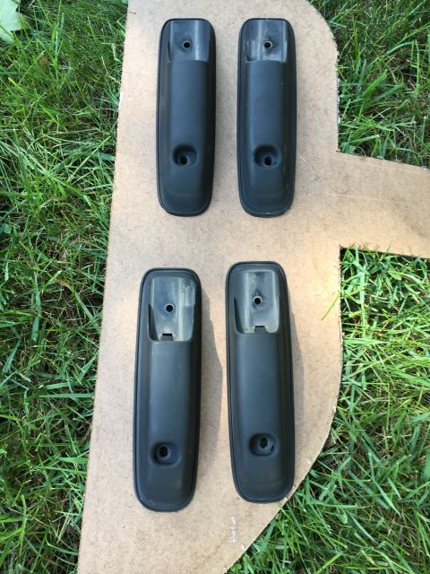 1996 Ford Bronco - Four black plastic car door handles are shown on a piece of cardboard with grass surrounding the area.