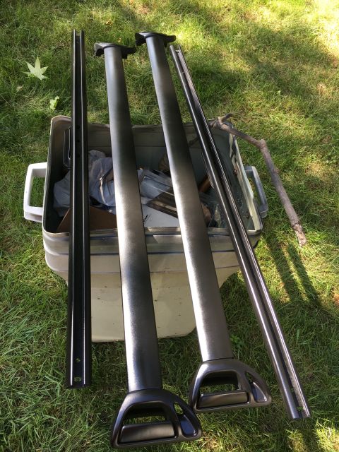 1996 Ford Bronco - Roof rack components, including crossbars and side rails, are laid out on grass next to a plastic storage bin.