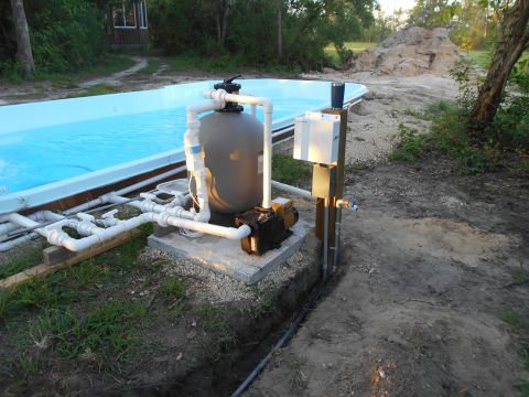 1992 Ford Bronco - A swimming pool pump and filter system is installed next to a partially filled pool, with plumbing and electrical components visible.