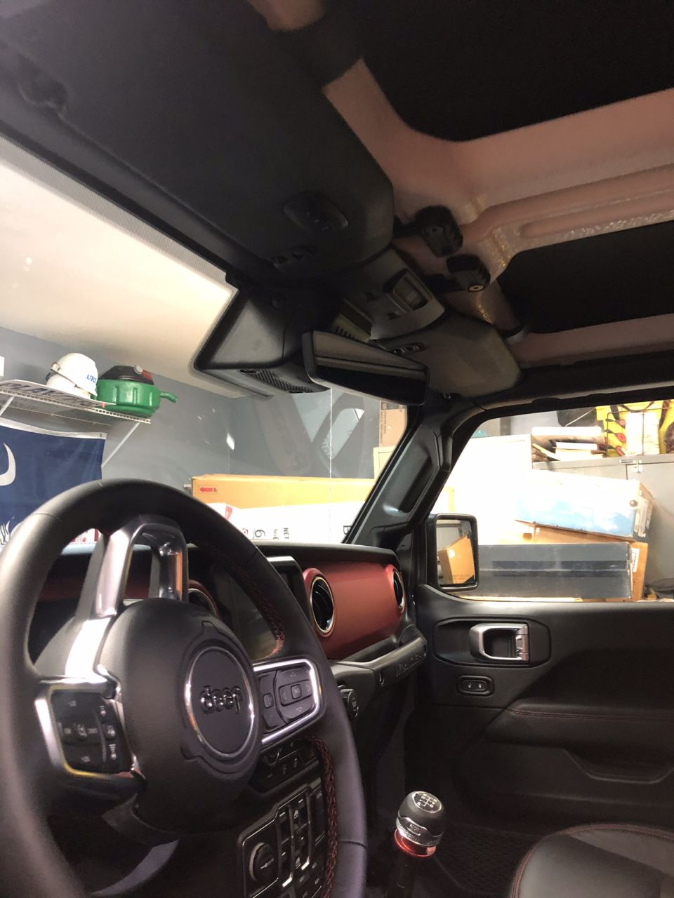 Jeep Wrangler interior with black steering wheel, red dash accents and open top