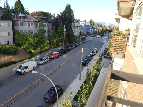 1978 Ford Bronco - An orange SUV is parked on a street lined with apartment buildings and trees.