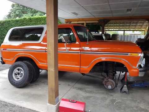 1978 Ford Bronco - This orange Ford Bronco is undergoing maintenance, with its front end raised on jack stands.