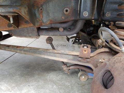 1978 Ford Bronco - Close-up view of heavily rusted undercarriage components, including suspension and exhaust parts.