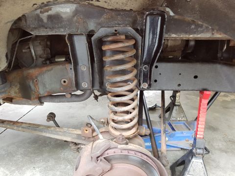 1978 Ford Bronco - Close-up view of the front suspension and brake assembly, showing the coil spring and associated frame components.