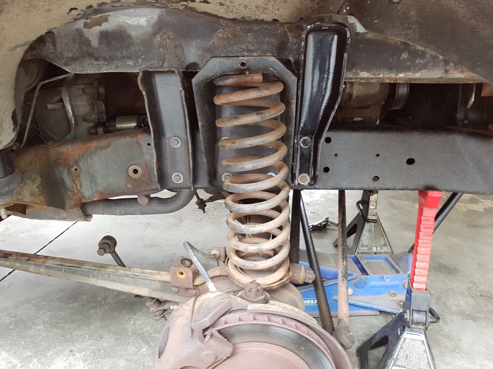 Front suspension components including coil spring, brake caliper, and frame structure