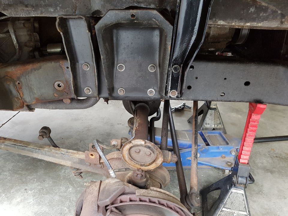 Underbody view of vehicle suspension and frame components, supported by jack stands