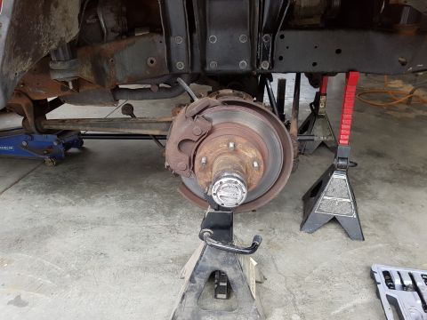 1978 Ford Bronco - The front suspension and braking system of a vehicle are supported by jack stands during maintenance.