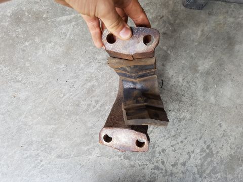 1978 Ford Bronco - A hand holds a fractured metal component, revealing its damaged state against a concrete background.