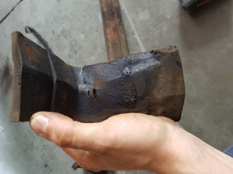 1978 Ford Bronco - A heavily rusted metal part is held in a person's hand against a concrete background.