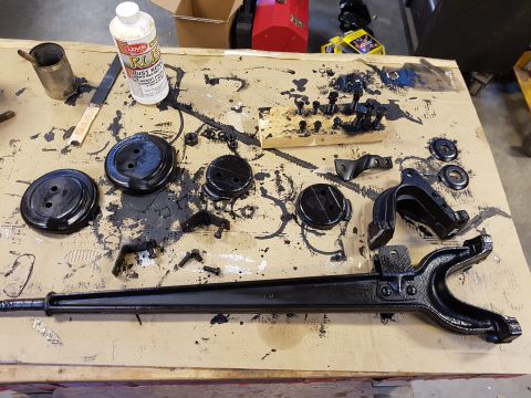 1978 Ford Bronco - Several automotive components are arranged on a table, some freshly painted black, alongside a bottle of rust remover.