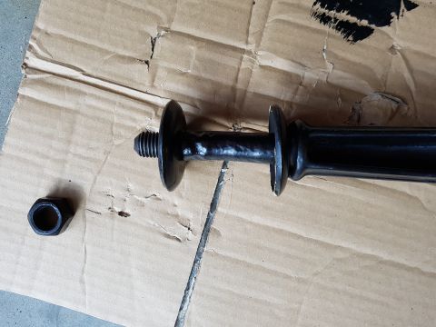 1978 Ford Bronco - Close-up of a black metal automotive part and a nut on a piece of cardboard.