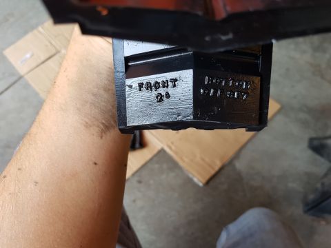 1978 Ford Bronco - A black metal part with visible text is held by a person's arm.