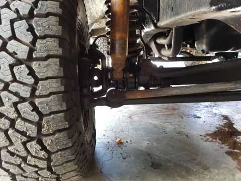 1978 Ford Bronco - Undercarriage view of a vehicle's front wheel assembly, including the tire, suspension, and steering components.