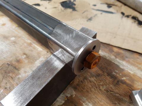 1978 Ford Bronco - A metal bracket is shown with a bolt and nut, resting on a wooden surface.