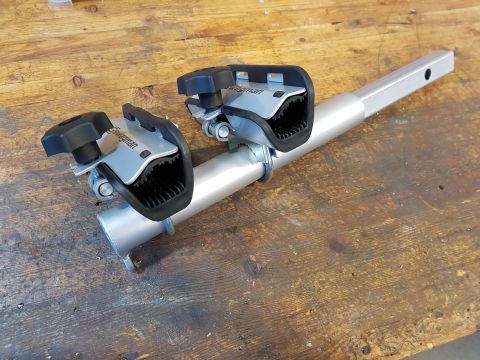 1978 Ford Bronco - A close-up view of a silver bike rack component two adjustable clamps with black grips.