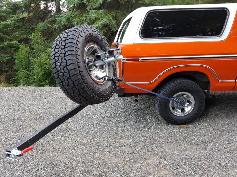 1978 Ford Bronco - The rear of an orange and white 1978 Ford Bronco is shown with a spare tire mounted on a carrier.