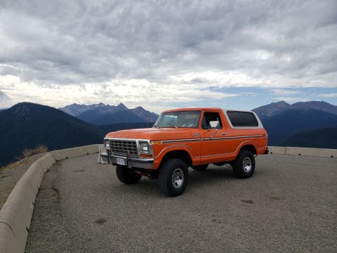 1978 Ford Bronco - An orange 1978 Ford Bronco with a white top is parked on a scenic mountain overlook.