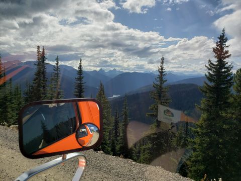 1978 Ford Bronco - Scenic mountain view from a vehicle's side mirror, with trees and clouds.