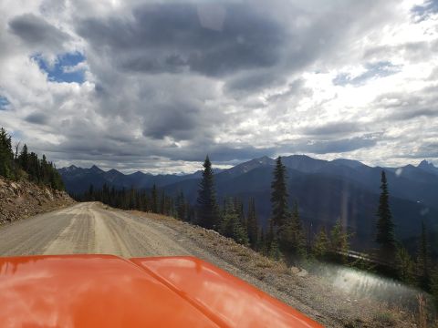 1978 Ford Bronco - Driving on a gravel road through a mountainous landscape under a cloudy sky.