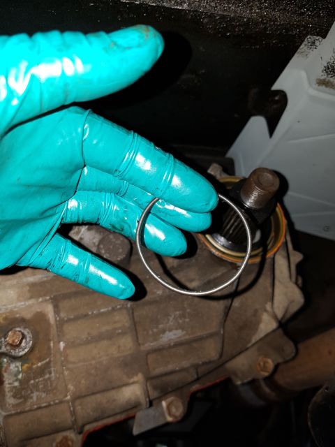 1978 Ford Bronco - A snap ring is held near a vehicle's transmission housing and output shaft.