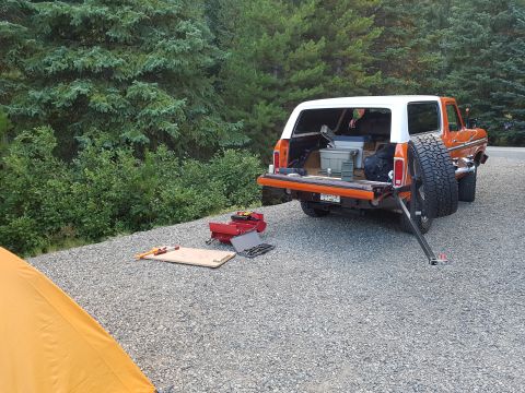 1978 Ford Bronco - 1978 Ford Bronco parked outdoors with its tailgate open, revealing storage items and tools laid out nearby.