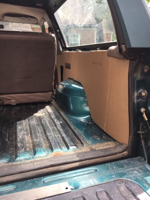 1996 Ford Bronco - Interior view of a 1996 Ford Bronco's cargo area, showing custom cardboard paneling and worn flooring.