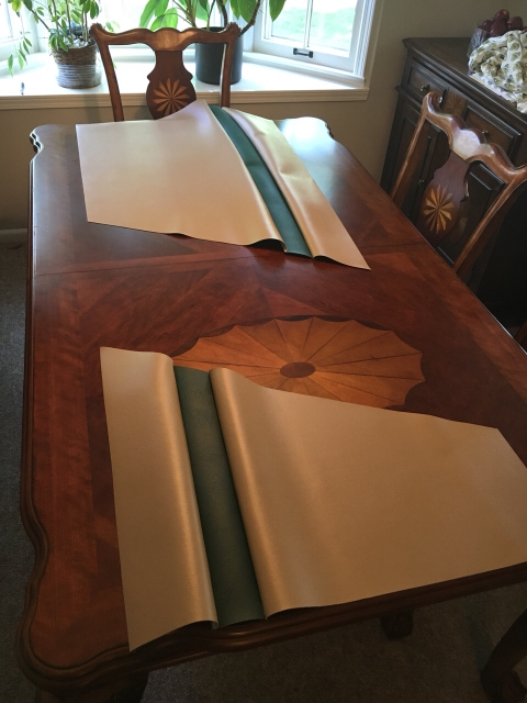 1996 Ford Bronco - A room scene shows a wooden table with material samples and chairs, with a window and plants in the background.