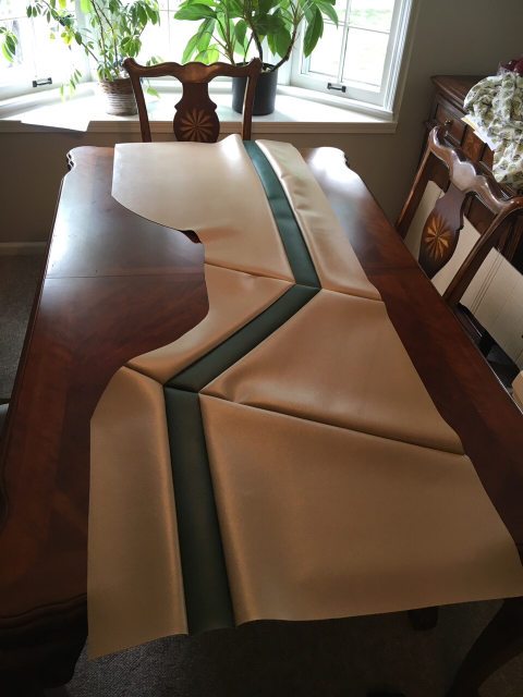 1996 Ford Bronco - Automotive upholstery panel with tan and dark green sections is displayed on a table.