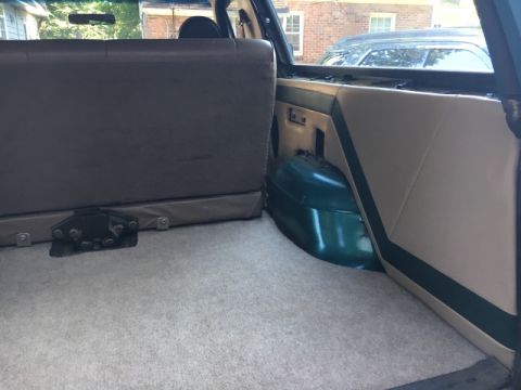 1996 Ford Bronco - Interior view of the cargo area in a 1996 Ford Bronco, showing the folded rear seat and a green wheel well.