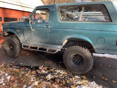 1996 Ford Bronco - This green Ford Bronco is shown from the side, aftermarket steps and off-road tires.
