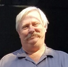 1990 Ford Bronco - Portrait of a man with a prominent mustache against a dark background.