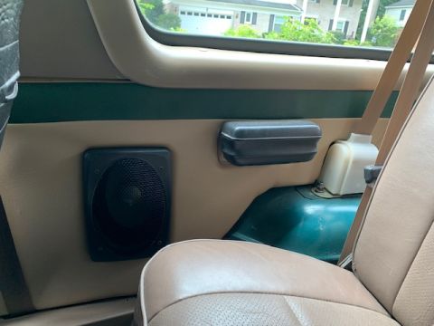 1996 Ford Bronco - The interior of the vehicle shows a tan door panel with a black speaker and a dark gray grab handle.