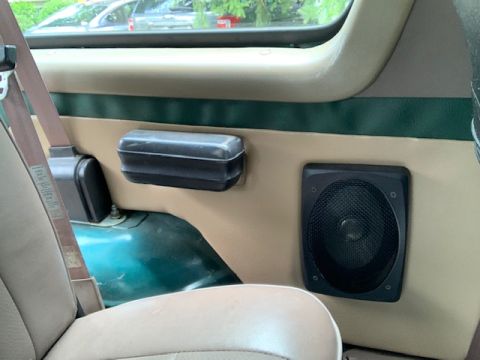 1996 Ford Bronco - Close-up of a vehicle's interior door panel, showing a speaker and armrest.