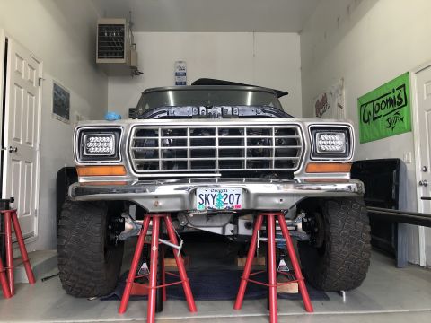 1979 Ford Bronco - Front view of a 1979 Ford Bronco undergoing maintenance in a garage, supported by jack stands.