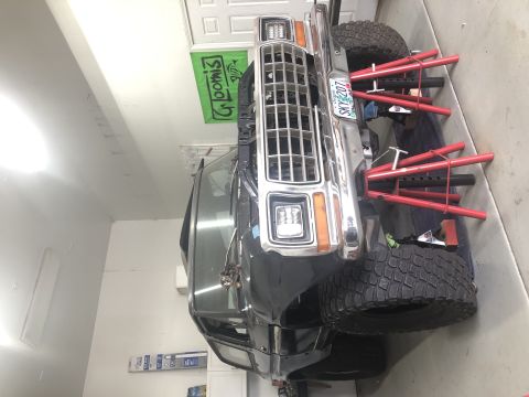 1979 Ford Bronco - The front of a 1979 Ford Bronco, a chrome grille and square headlights, is shown in a garage setting.