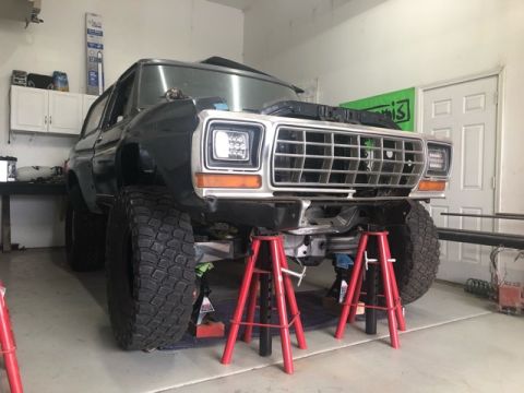 1979 Ford Bronco - This Ford Bronco is elevated on jack stands, its front end and large tires within a workshop setting.