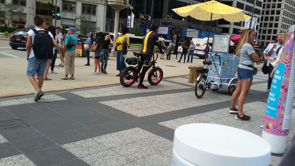 Electric bicycle with red-rimmed wheels parked on sidewalk
